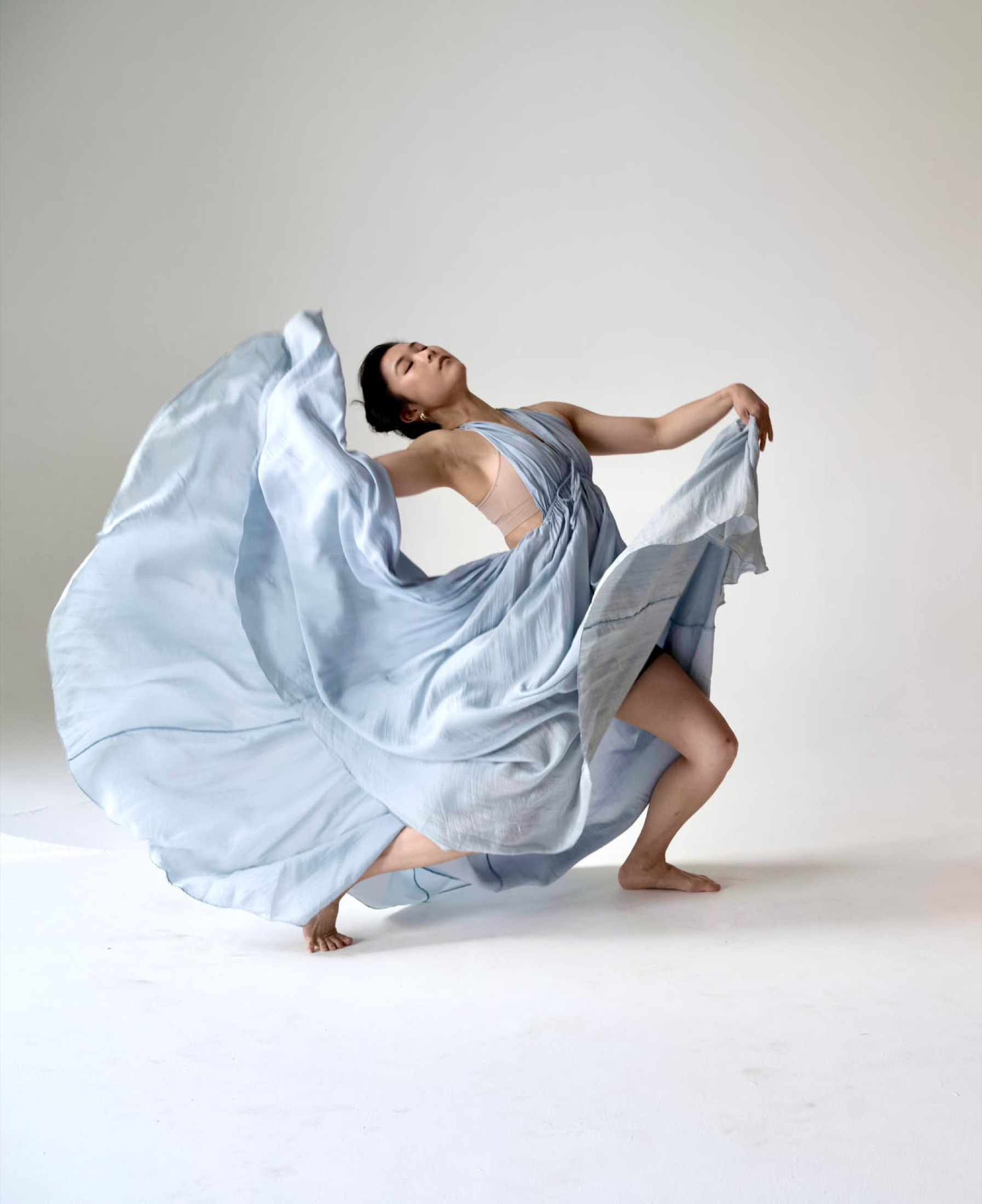 Hannah Jew mid-turn, a pale blue dress sweeping around her
