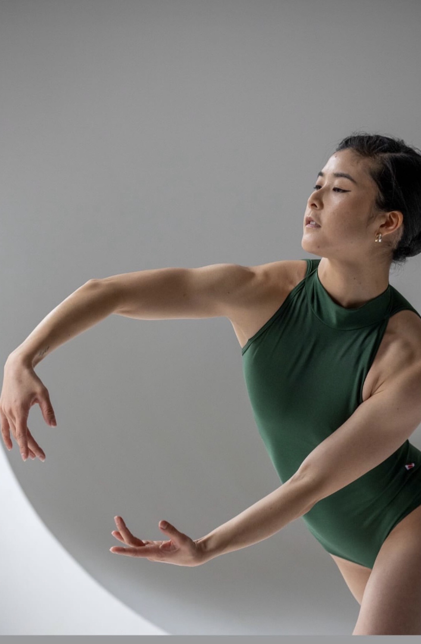 Hannah Jew in a green leotard, arms curved in a sculptural contemporary shape