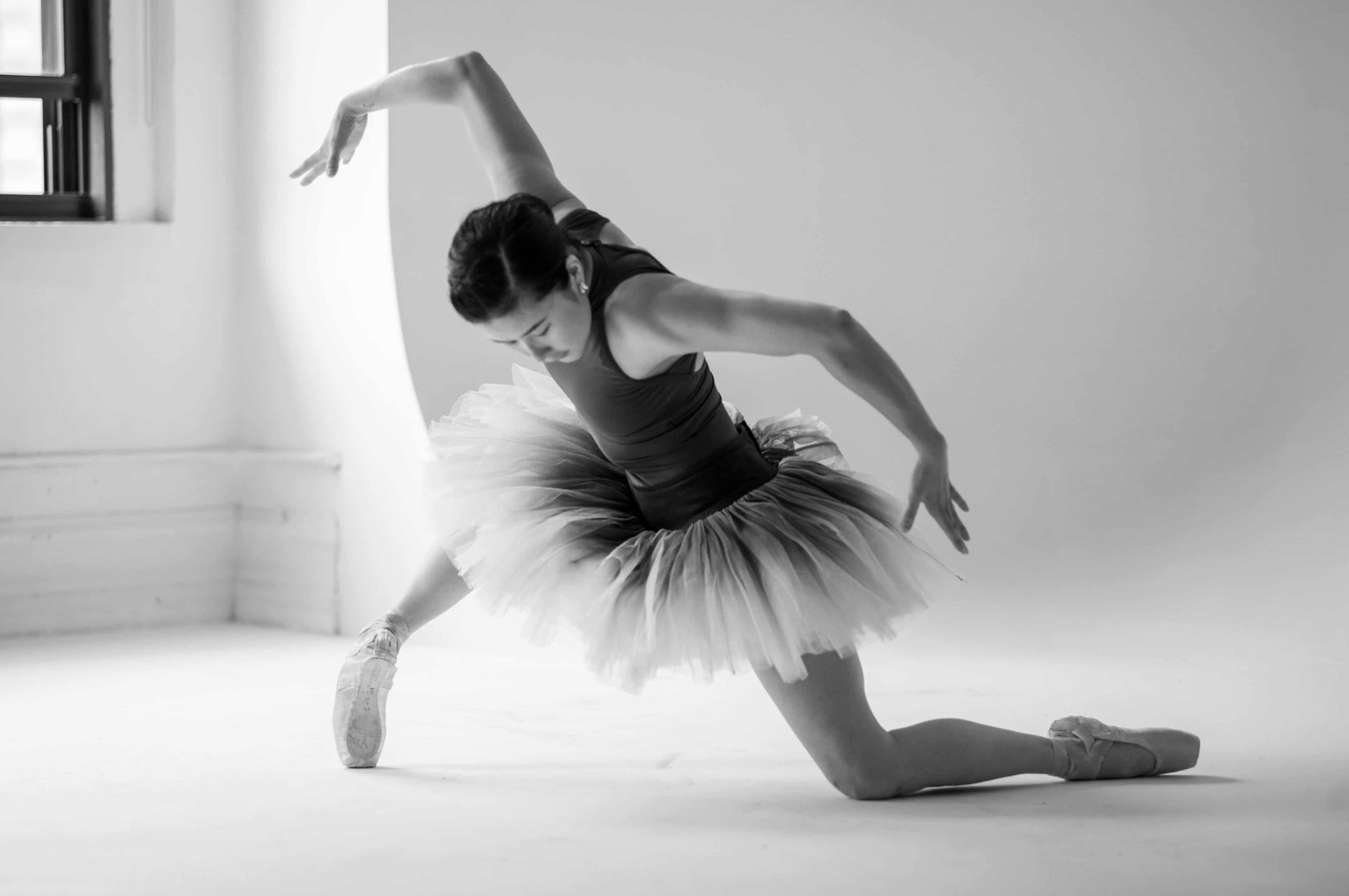 Hannah Jew in a tutu and pointe shoes, folded forward in an expressive pose