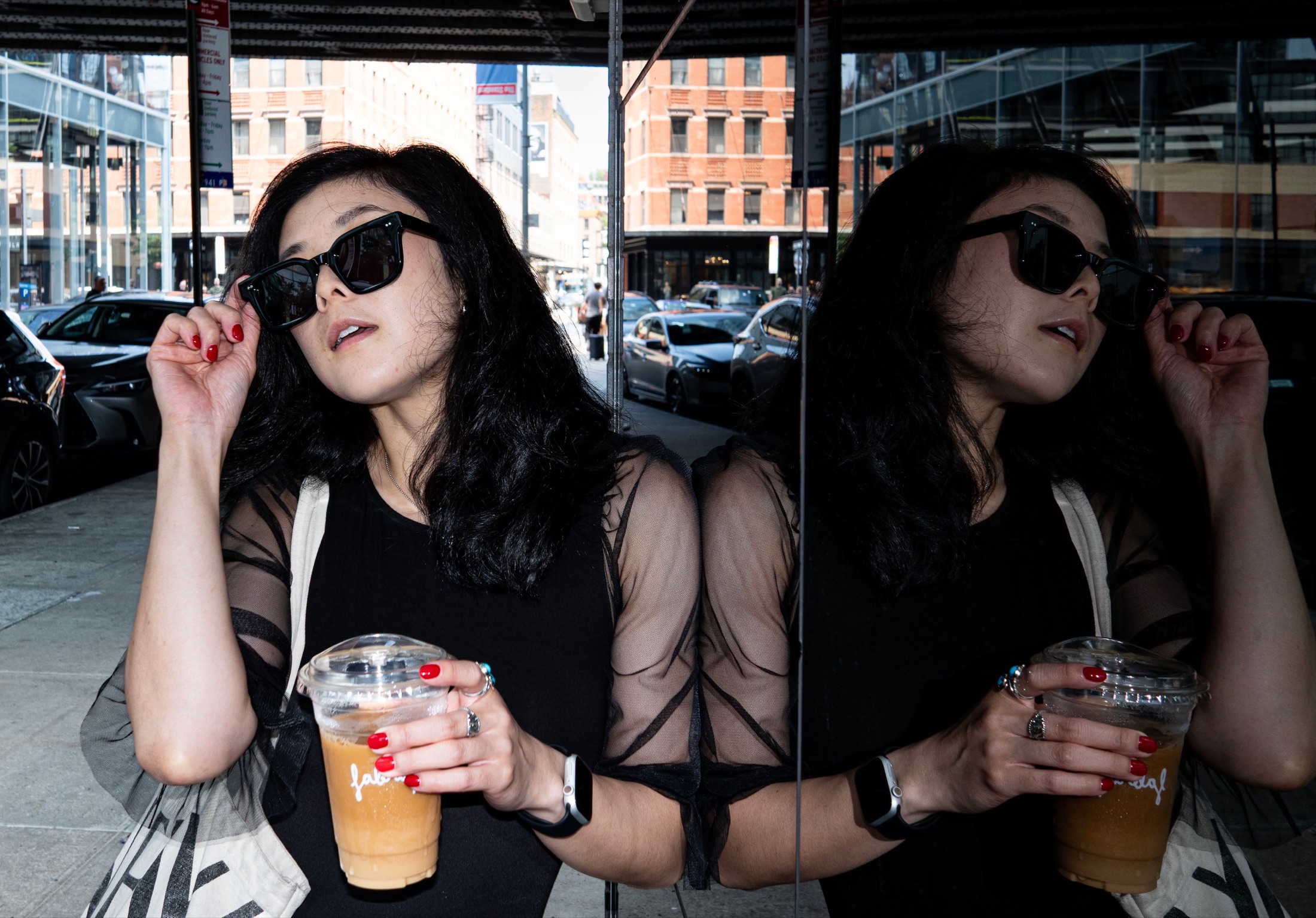 Hannah in sunglasses reflected in a mirrored wall on a New York street